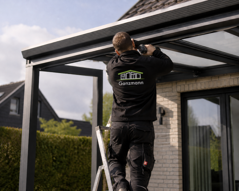 Monteur von GANZMANN montiert eine Terrassenüberdachung auf einer Leiter