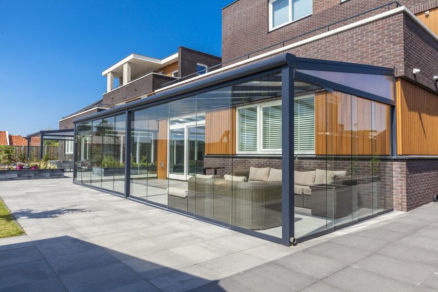 Wintergarten mit umlaufender Verglasung und anthrazitfarbenem Aluminiumrahmen an einem Wohnhaus