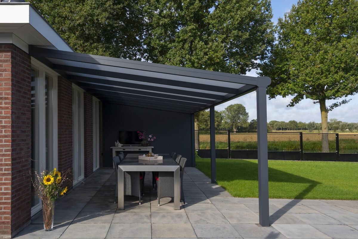 Terrassenüberdachung aus Aluminium mit Glasdach an einem modernen Wohnhaus mit Blick ins Grüne