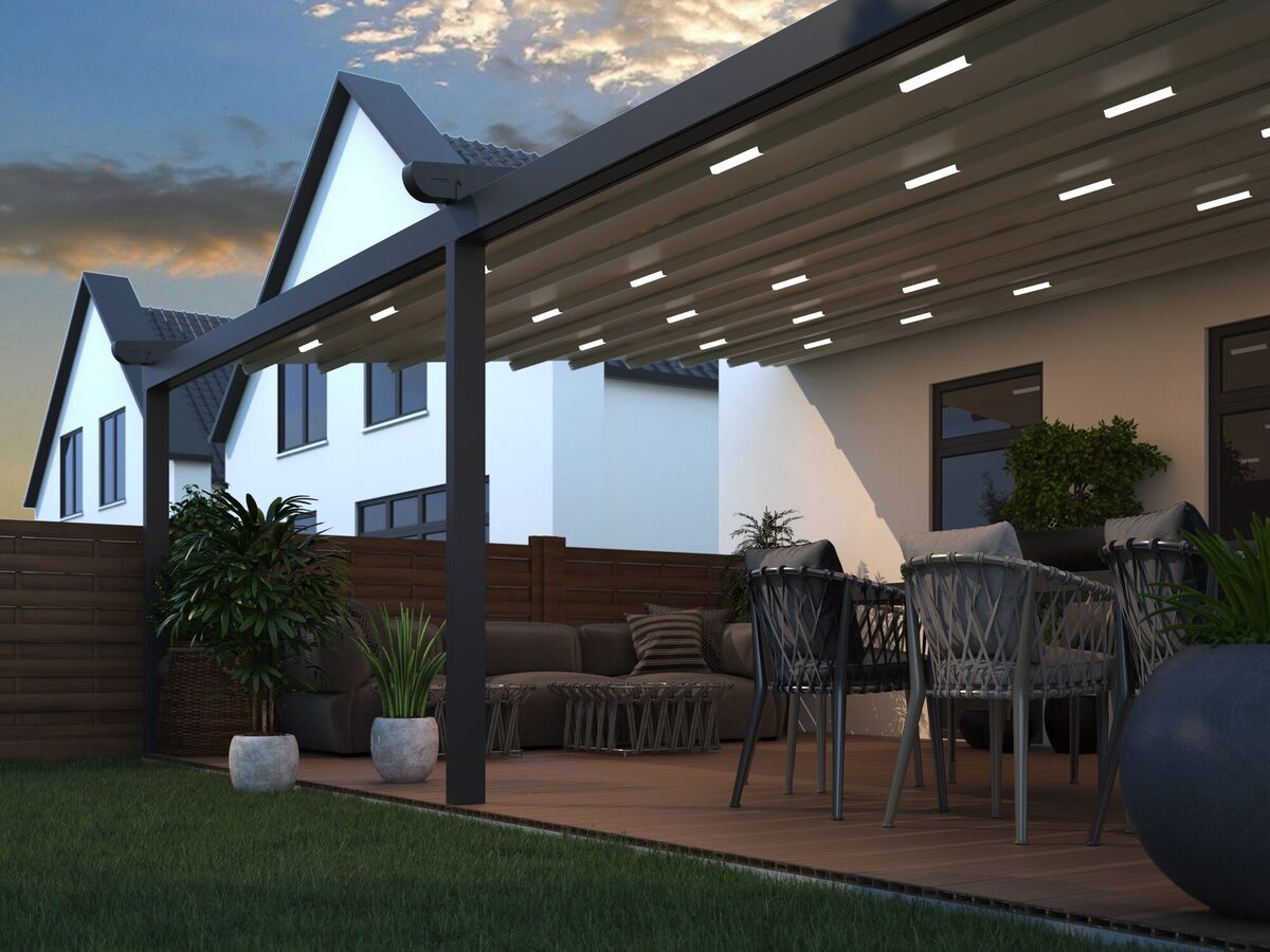 Beleuchtete Terrassenüberdachung mit LED-Spots am Abend über Ess- und Loungebereich