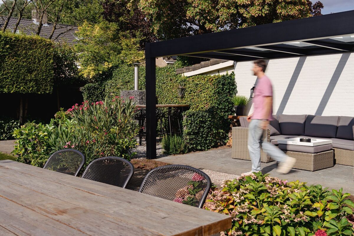 Freistehende Terrassenüberdachung mit Loungebereich in einem gepflegten Garten