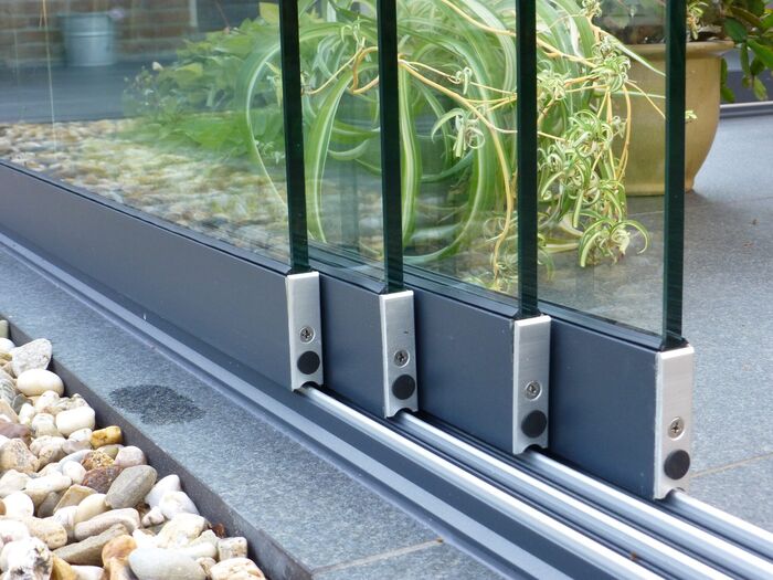 Detailaufnahme der Laufschienen einer Glasschiebewand mit Entwässerungsrinne