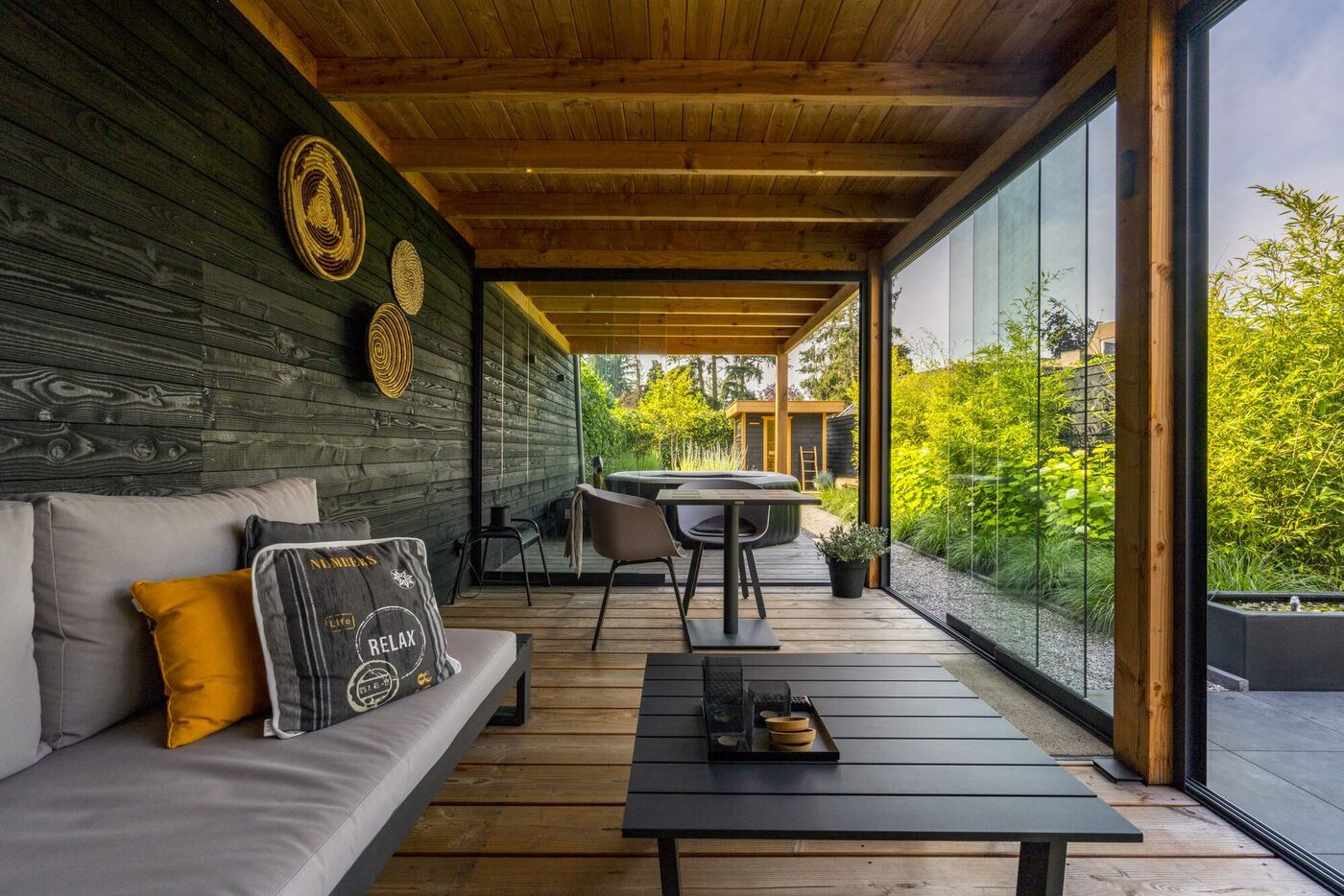 Überdachte Terrasse mit Holzdecke, Loungemöbeln und Blick in den Garten – Projekt von GANZMANN